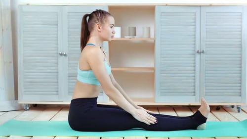 Young Woman Stretching on Yoga Mat Indoors