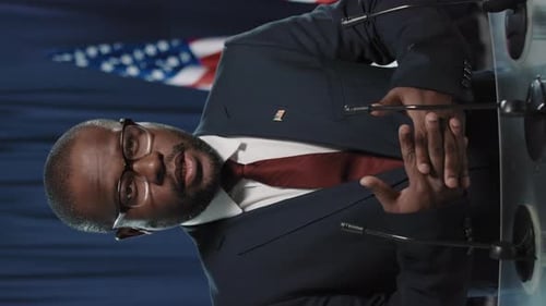 Man Speaks at Podium with American Flags