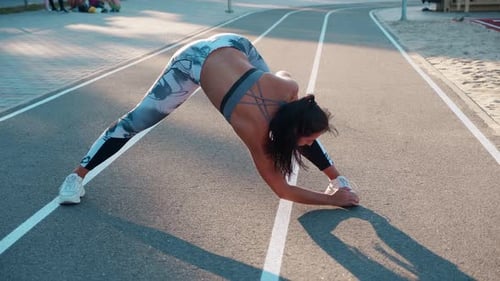 Athletic Woman Stretching on Running Track