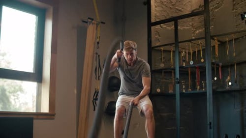 Strong Sportsman Using Battle Ropes in Fitness Center. Man Training at Gym