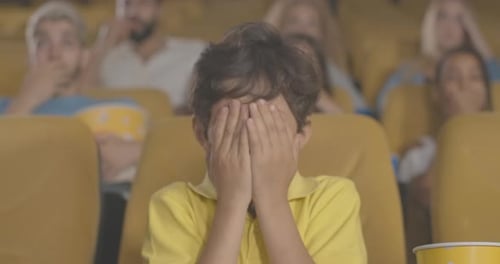Portrait of Scared Middle Eastern Boy Closing Eyes in Cinema. Absorbed Child Watching Frightening
