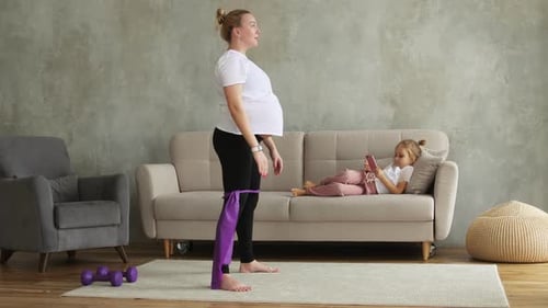 Pregnant Woman Doing Squats with Resistance Band at Home