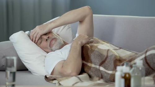 Senior Man Resting with Headache on Couch