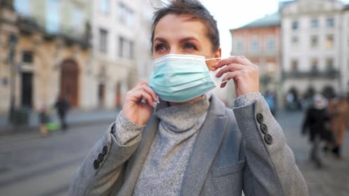 Woman Puts On Mask in City Environment