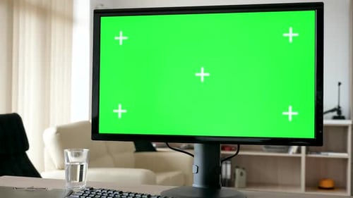 Unrecognisable Man Looking at Modern Personal Computer with Big Green Screen Chroma Mock Up