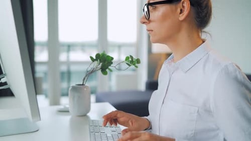 Woman Typing on Keyboard in Office at Computer