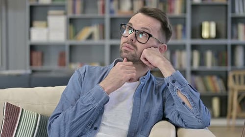 Man Sitting on Couch, Deep in Thought