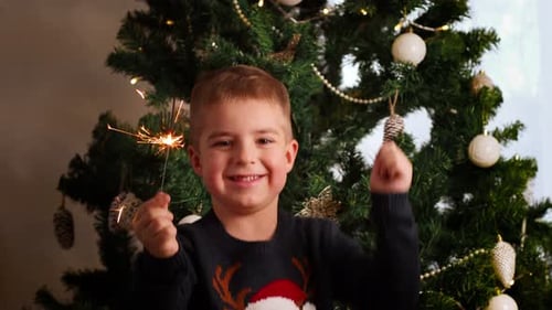 Happy Child with Sparkler by Christmas Tree