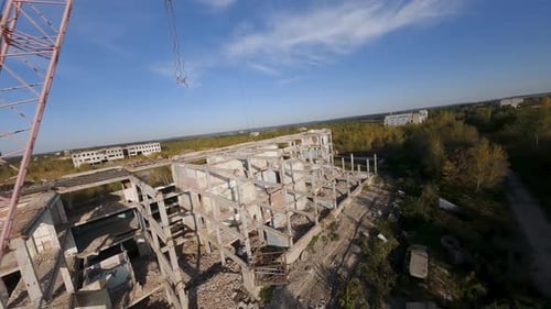 FPV-Drohne fliegt schnell und wendig zwischen verlassenen Industriegebäuden und um eine