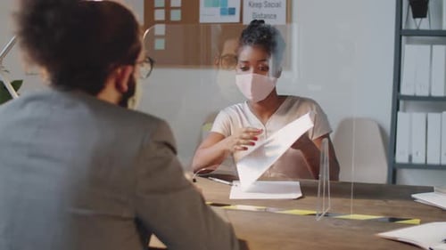 Adults Review Paperwork in Office with Partitions