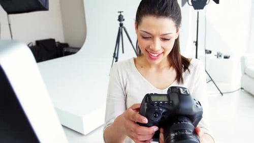 Smiling Photographer Checks Camera in Bright Studio