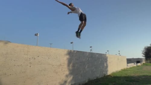 Young Man Doing Backflip From Concrete Wall