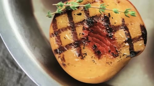 Pêches grillées biologiques au thym frais sur une plaque métallique.