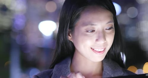 Woman Using Tablet at Night in City