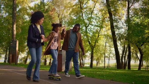 Parents Teaching Girl Riding Longboard in Park