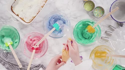 Flat lay. Mixing food coloring into Italian buttercream frosting.