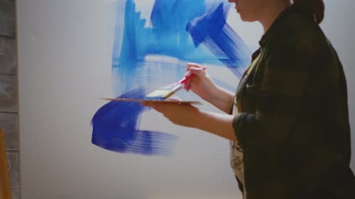 Woman Painting an Abstract with Blue on Canvas