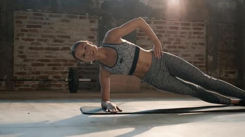 Fitness woman doing side plank exercise workout in gym indoors