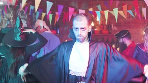 Als Vampir verkleideter junger Mann tanzt auf einer Halloween-Party lustig