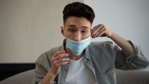 Young Man Putting On a Protective Face Mask