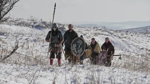 Group of Vikings with Shields and Swords Going Forward on the Winter Meadow