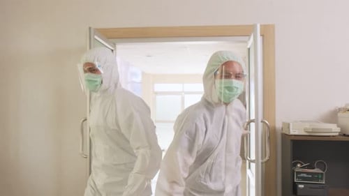 Emergency paramedic doctors wear PPE, open door coming to cure severe condition patient in hospital.