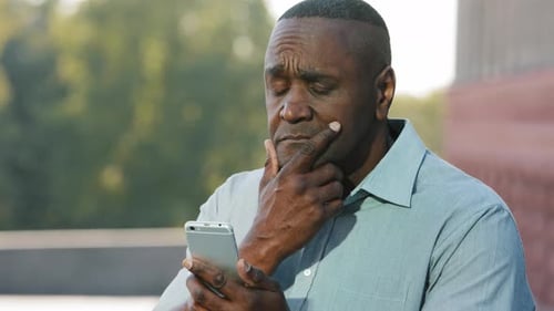 Man Contemplating a Problem on Mobile Phone
