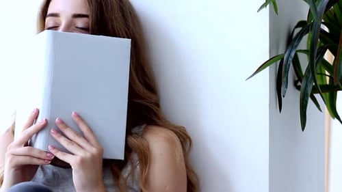 Happy Young Woman Reading Book At Home