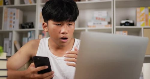Young Adult Working with Laptop and Phone Indoors