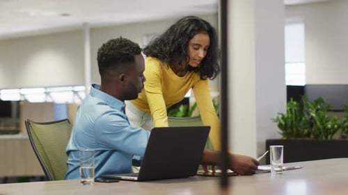 Coworkers Collaborate on Documents and Laptop in Office