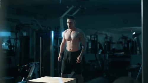 A Handsome Young Muscular Sportsman is Doing Exercise on a Fitness Machine in the Gym