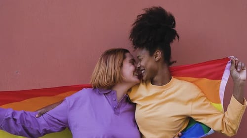 Young Couple Smile with Pride Flag Outdoors