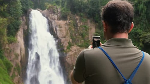 Adult Filming a Tropical Waterfall with Phone