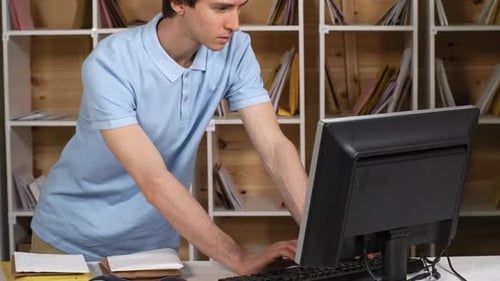 Young Male Post Office Clerk Registering Letters on Computer