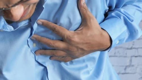 Young Man Suffering Pain in Heart and Holding Chest with Hand