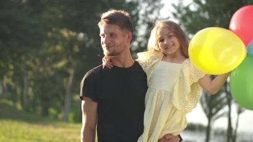 Father and Daughter Stroll With Balloons in Park