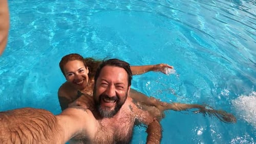 Happy caucasian people couple have fun and enjoy the swimming activity at the pool