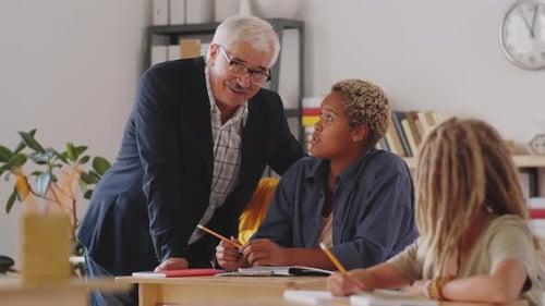 Teacher Helping Student at Desk in Classroom