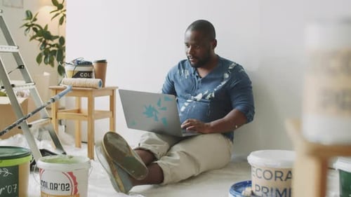 Man Sits on Floor with Laptop Renovation Concept