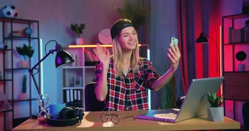 Rubia moderna con un pendiente en la nariz haciendo una videollamada en el móvil con un amigo