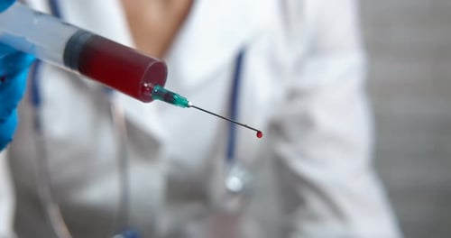 Médico com seringa de sangue.
