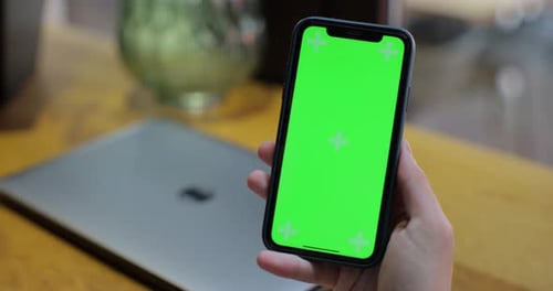Green Screen Phone Held Above Laptop