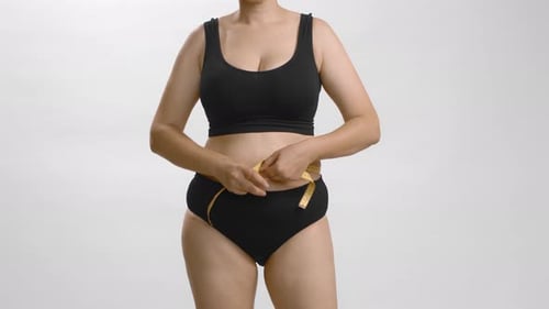 Mujer caucásica con exceso de peso con cinta métrica alrededor de su cintura