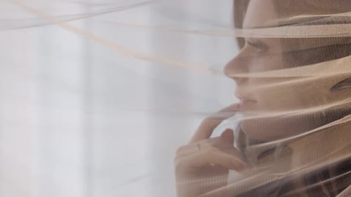Woman Behind a Sheer Curtain Looking Towards Window