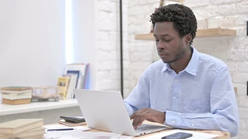 Young Adult Working at Laptop in Bright Office