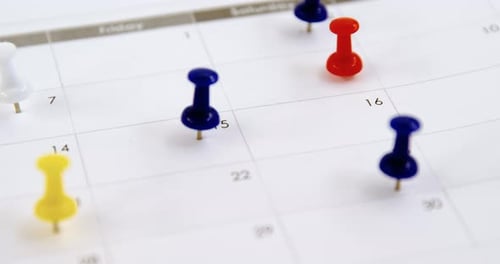 Colorful Push Pins Stuck into a Paper Calendar