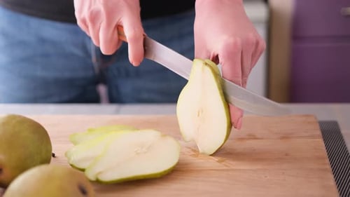 Cutting Slicing Fresh Pear with Knife on a Domestic Kitchen