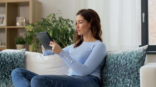 Woman Relaxes on Couch Using Tablet Device