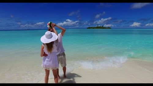 Teenage lovers in love on exotic coast beach trip by aqua blue water and white sandy background of t