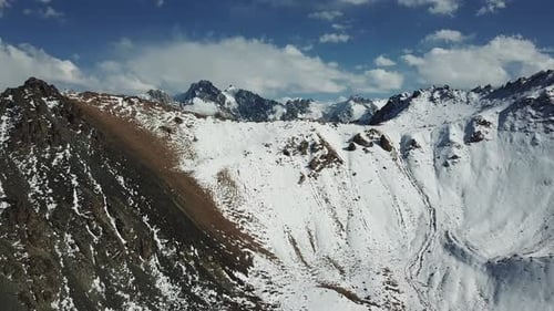 Riesige Berge mit Schnee bedeckt. Panorama der Berggipfel, blauer Himmel mit weißen Wolken